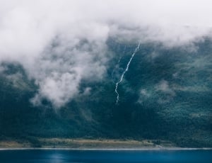 photo of lightning on mountain beside lake covered with fogss thumbnail
