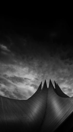 Greyscale Lowangle Photo of Pointed Structure Under Cloudy Sky thumbnail