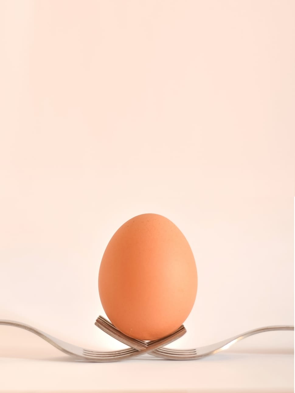 orange egg on top of two gray steel fork preview
