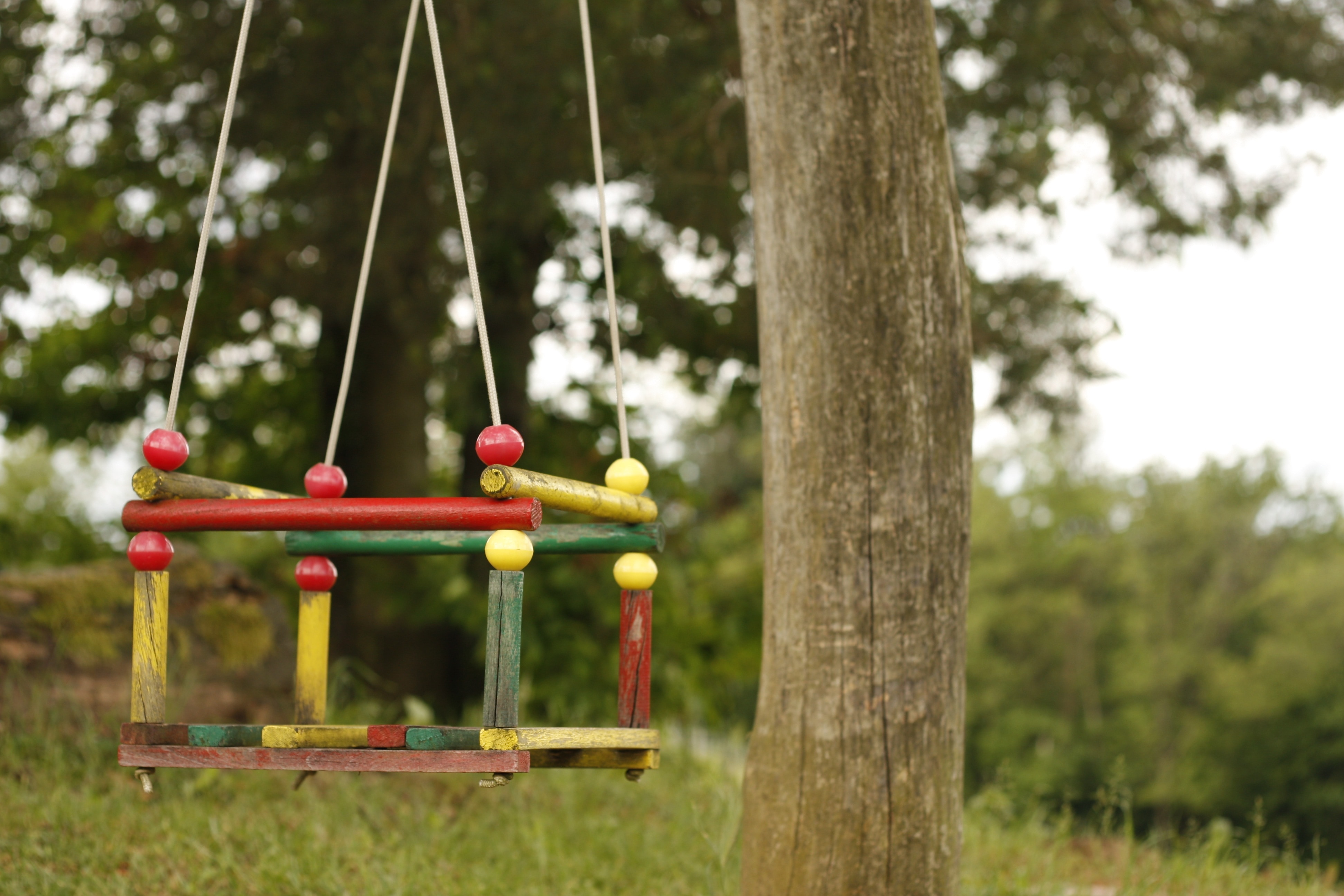 red, green, and yellow wooden swing chair