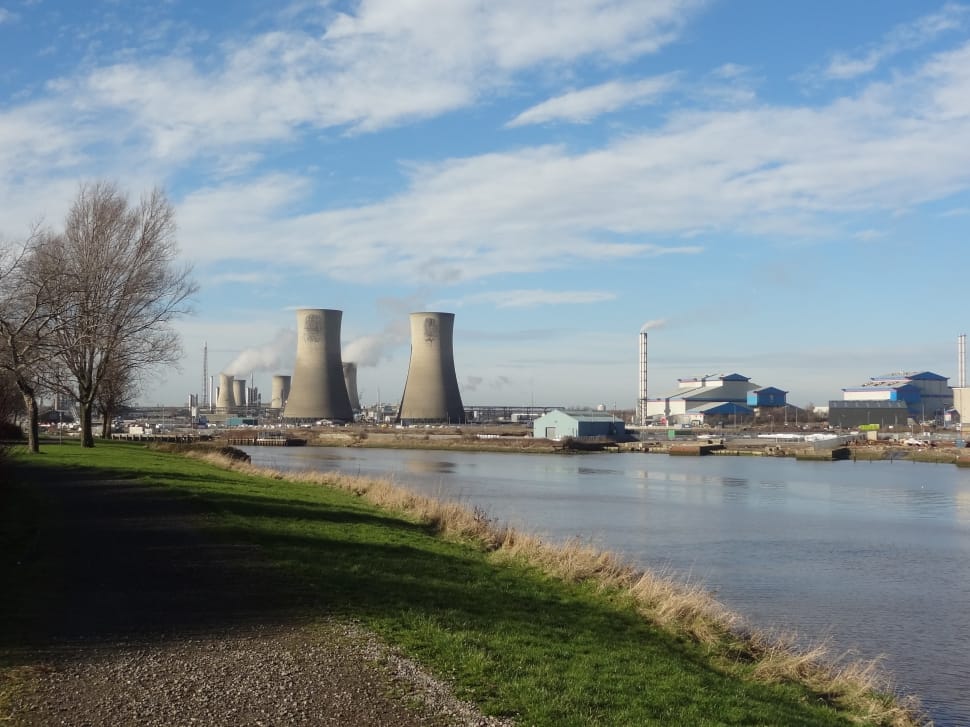 river between grey industrial building and grey trees and road preview