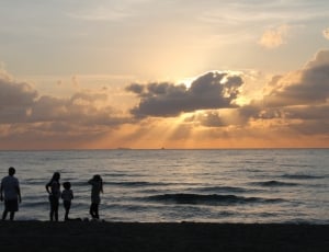 silhouette of 4 people near body seashore thumbnail