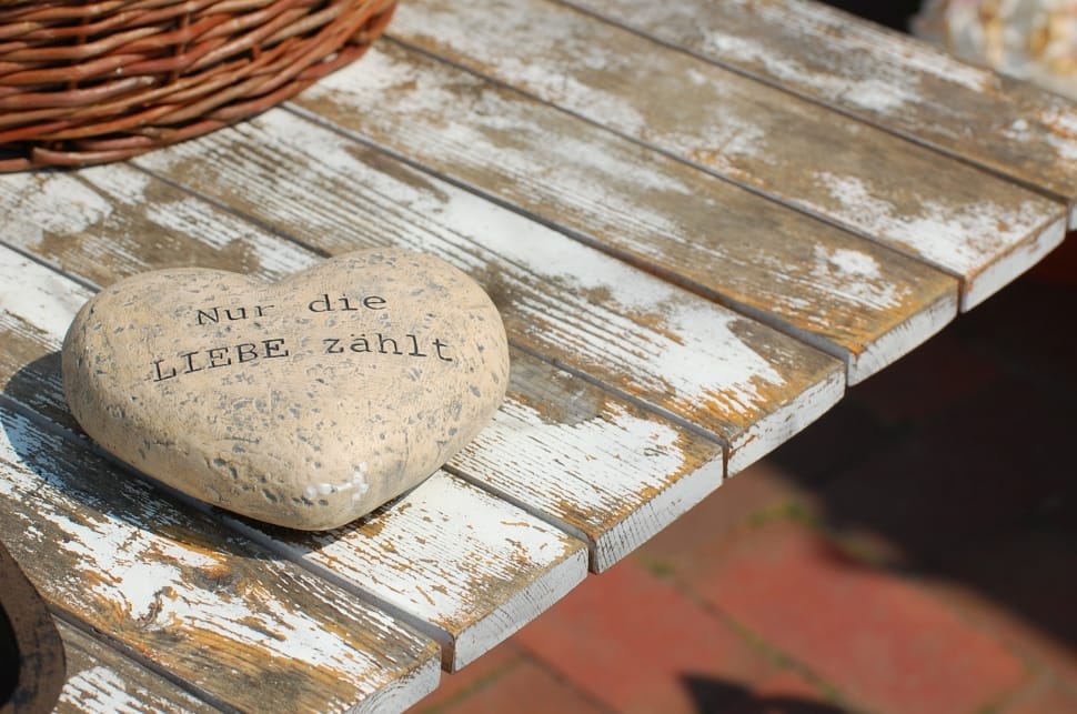 gray heart shape printed stone on top white and brown wooden table preview
