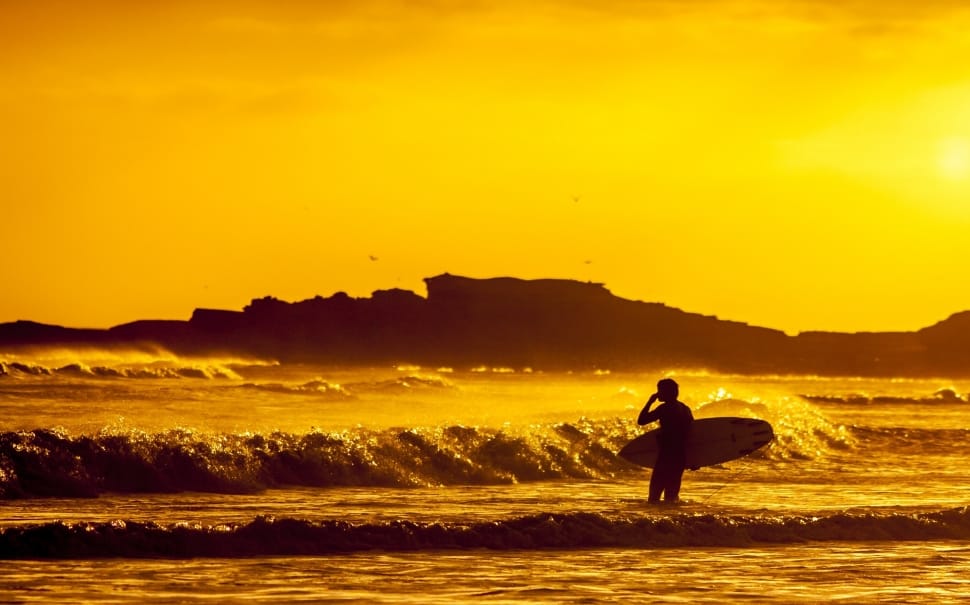 silhouette of person carrying surfboard in seashore preview