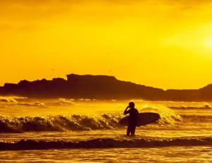 silhouette of person carrying surfboard in seashore thumbnail
