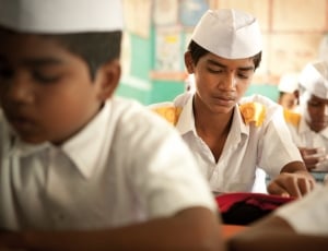 selective focus photography of boy sitting wearing uniform with other classmates thumbnail