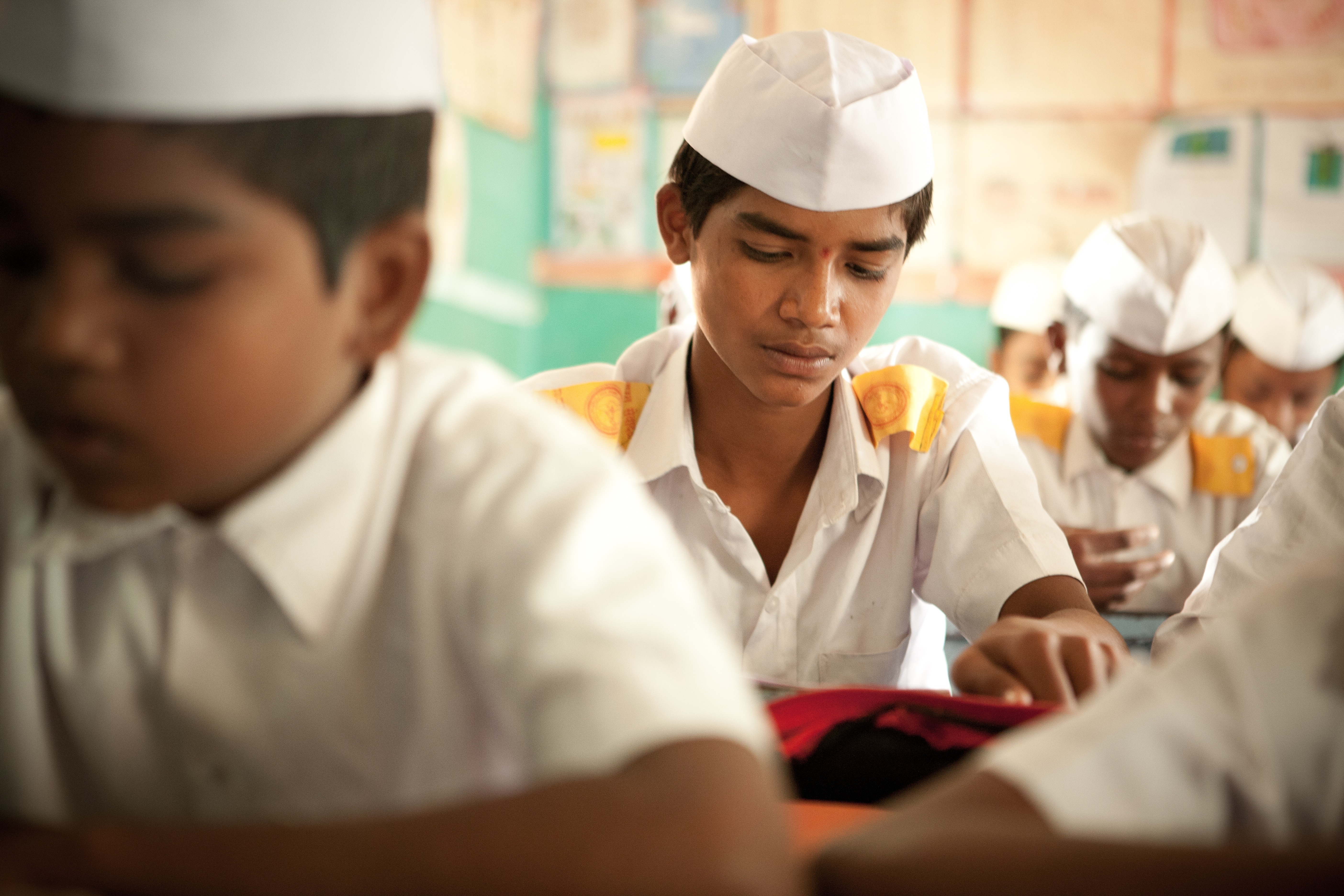 selective focus photography of boy sitting wearing uniform with other classmates