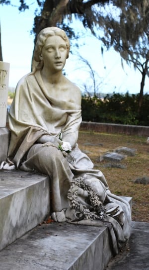 selective focus photography of woman statue sitting on tombstone thumbnail