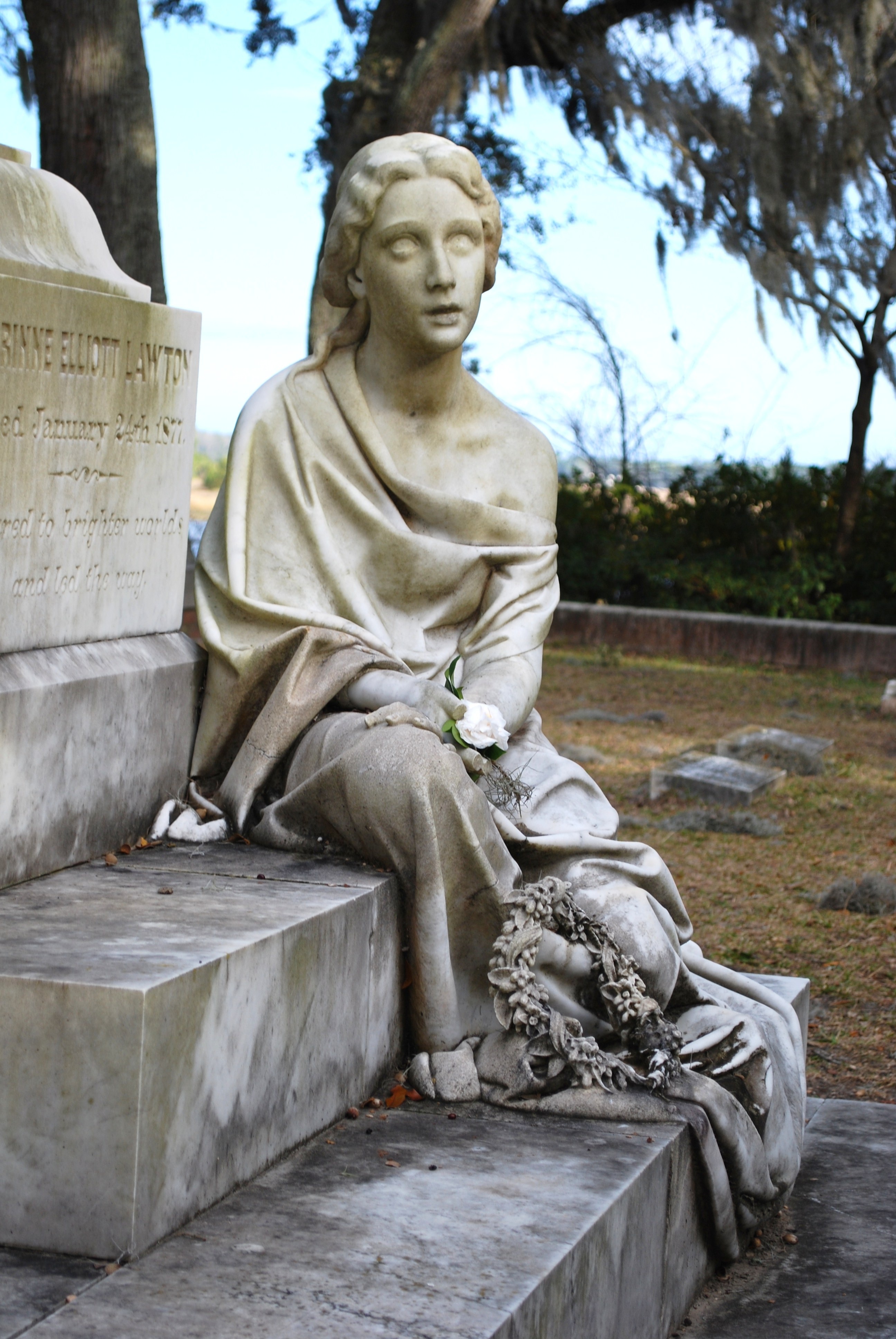 selective focus photography of woman statue sitting on tombstone