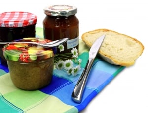 sliced bread beside bread knife near three glass food containers thumbnail