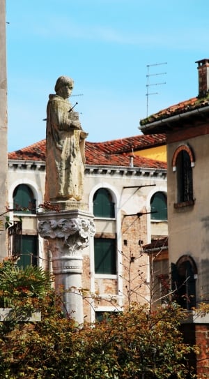 religious man statue near concrete buildings during daytime thumbnail