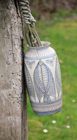 white and teal fish print vase near green lawn grass during daytime thumbnail