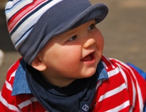 boy wearing white and red stripe shirt and cap outdoor while smiling during daytime thumbnail
