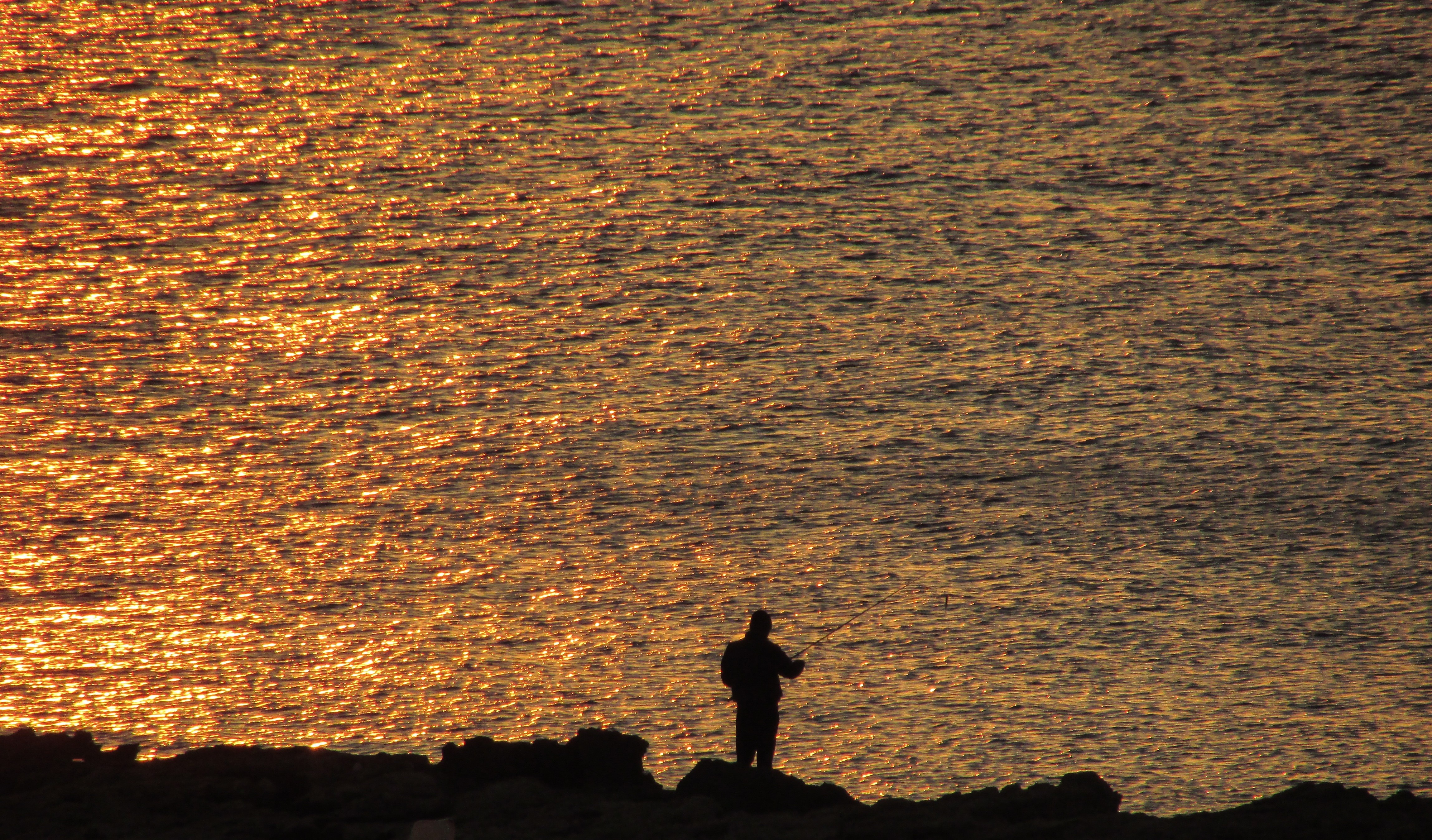 silhouette of man near body of water