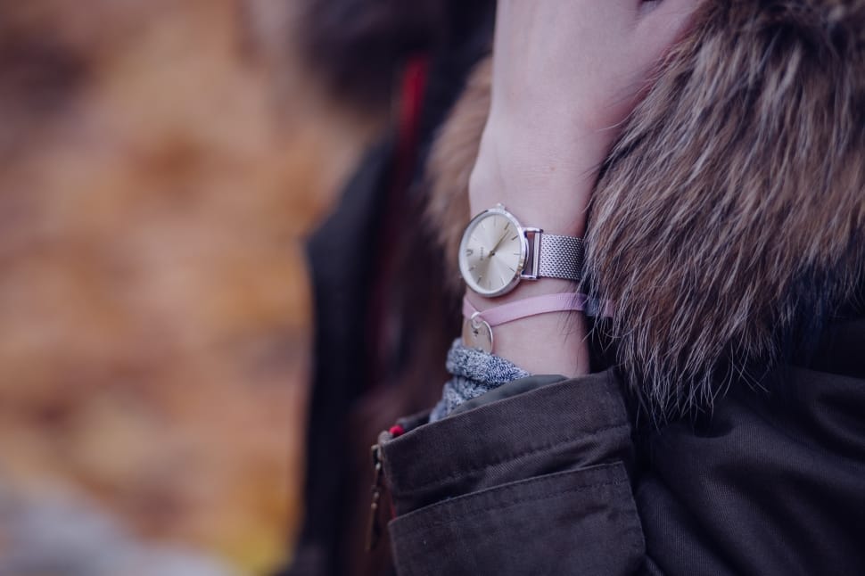 person wearing black-and-brown fur coat with pink bracelet and silver analog watch in left arm preview