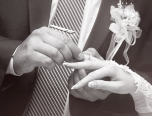 gray scale photo of groom placing the ring to his bride thumbnail