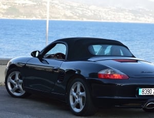 black sports car near ocean during daytime thumbnail