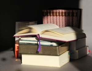 pink covered book open on top of stack of books thumbnail