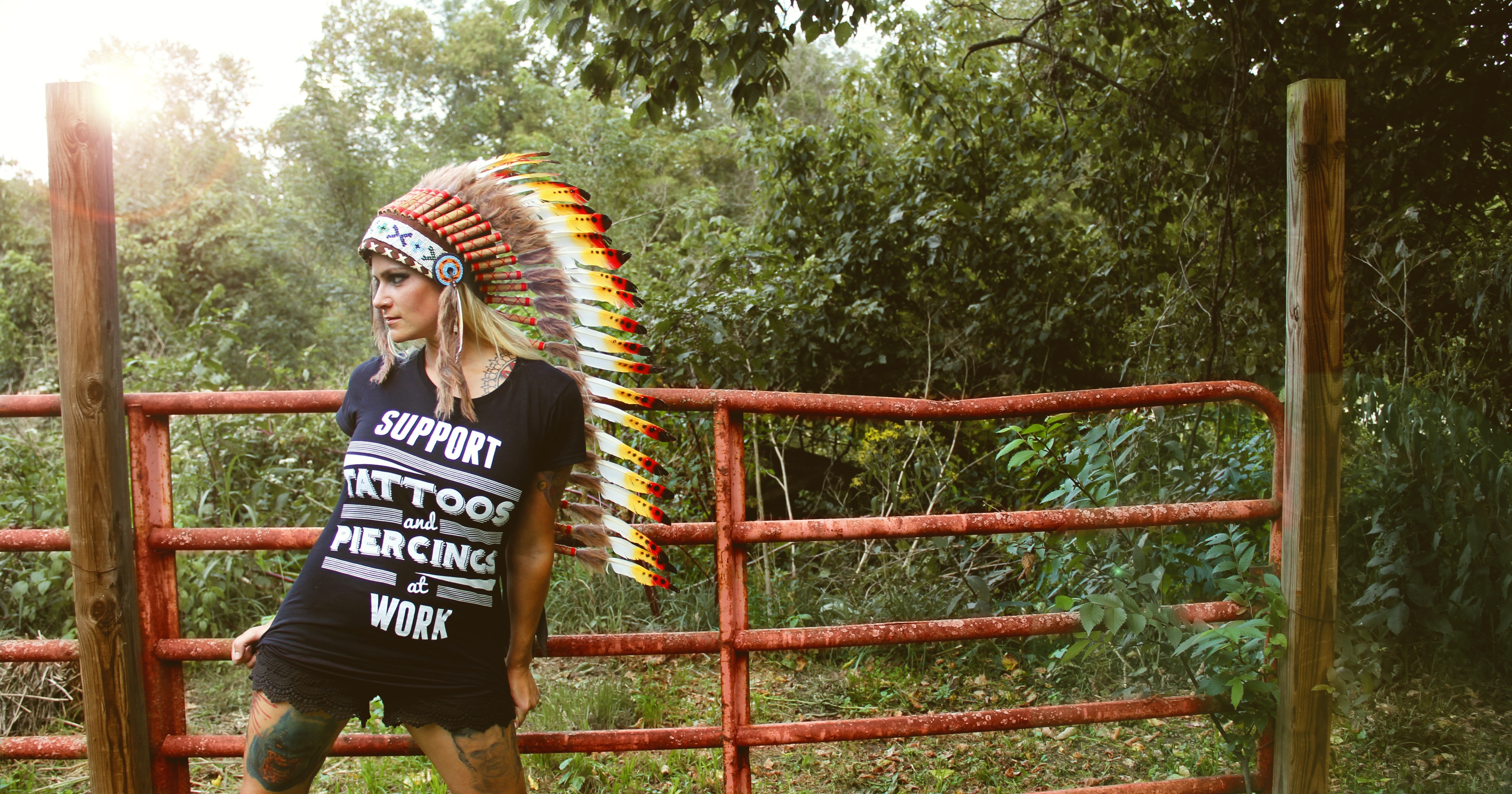 woman standing near fence with Native American head dress