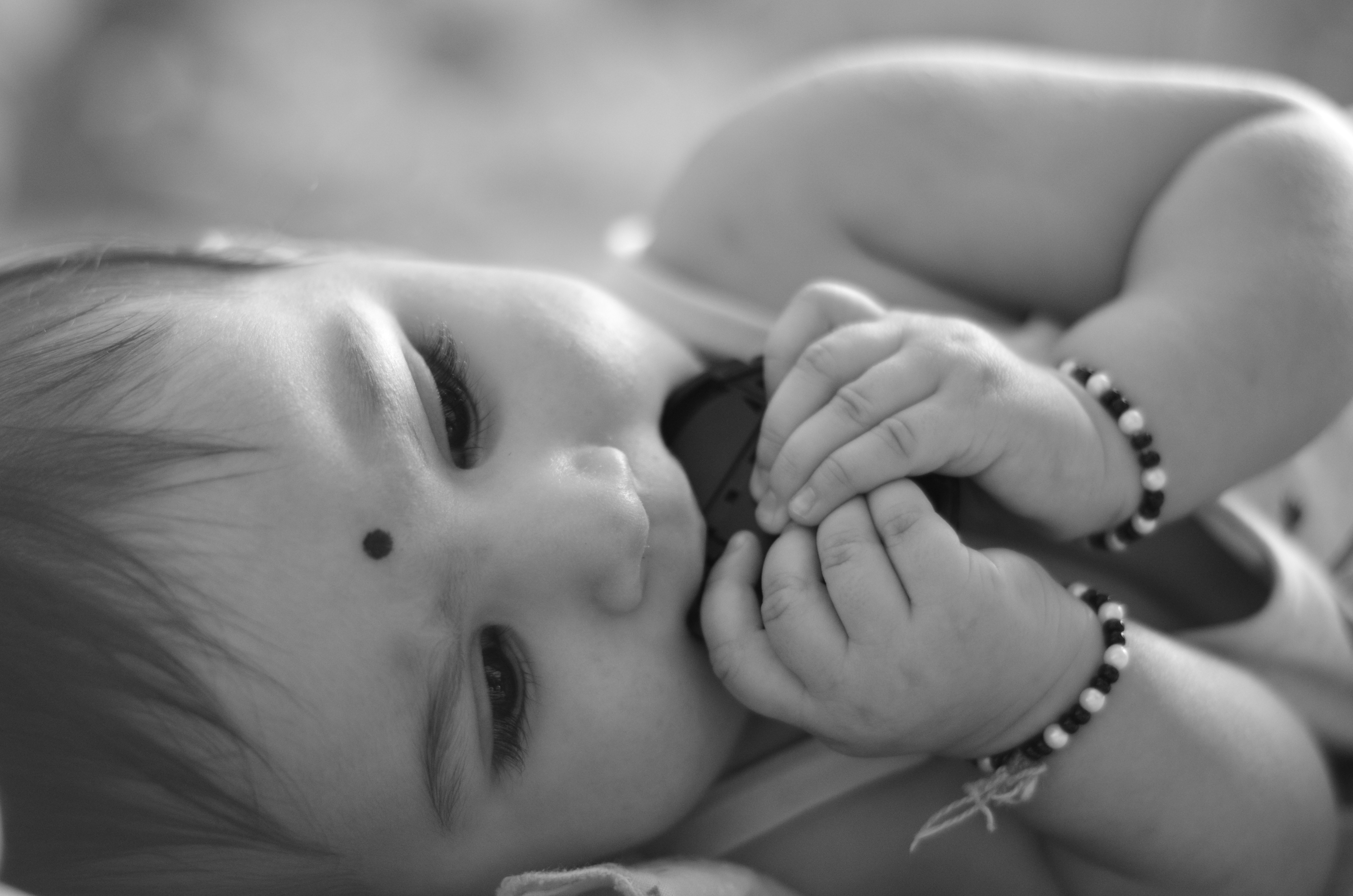 baby with bracelets grayscale photography
