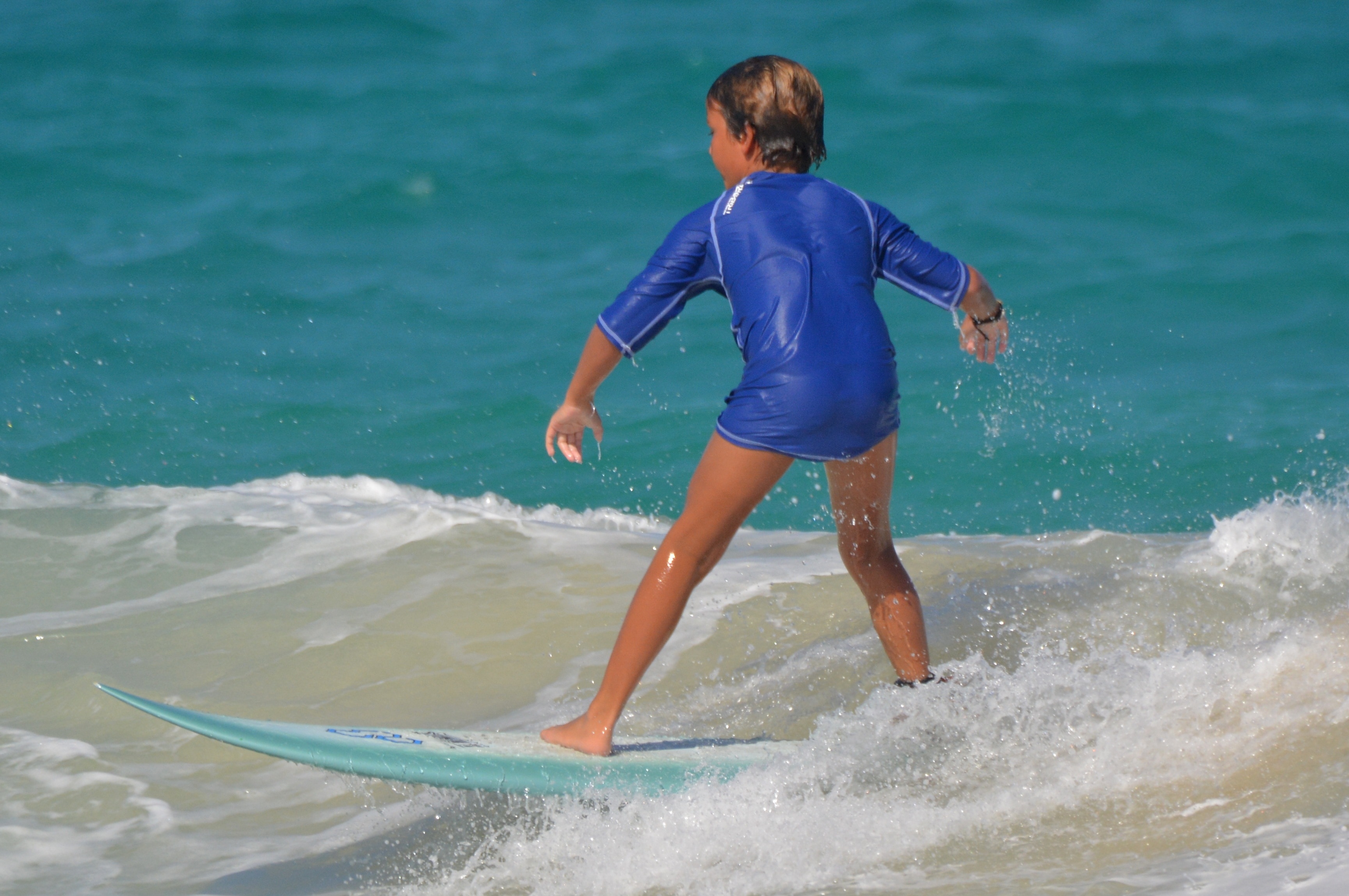 boy in blue surfing on blue sea