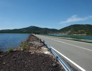 gray concrete bridge along the body of water during daytime thumbnail