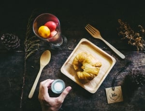 person holding gray tool with croissant and spoon and fork thumbnail