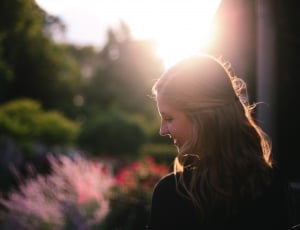smiling woman in black top across garden posing for photo during daytime thumbnail