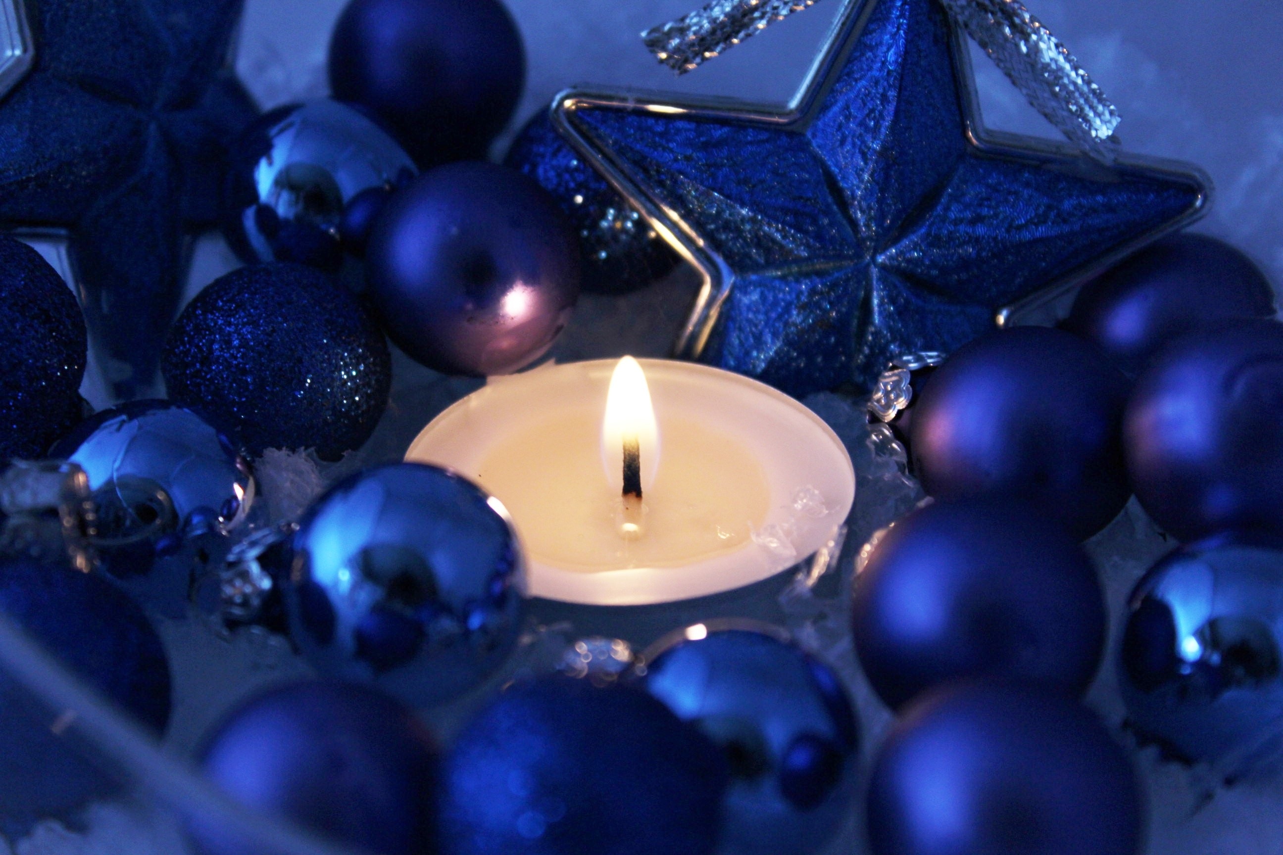 white candle beside blue beads