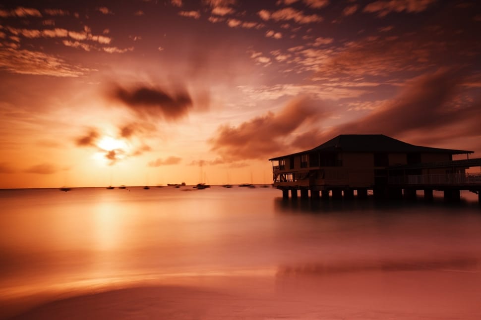 silhouette of house in ocean water during sunset preview