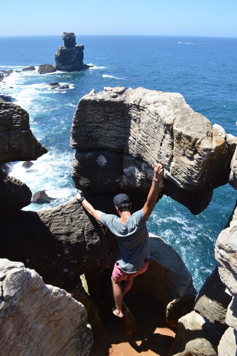 man in gray gray t-shirt and pink shorts climbing on rocks near sea preview