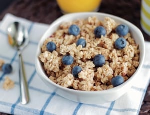 cereal and blueberries on white ceramic bowl beside stainless steel spoon thumbnail