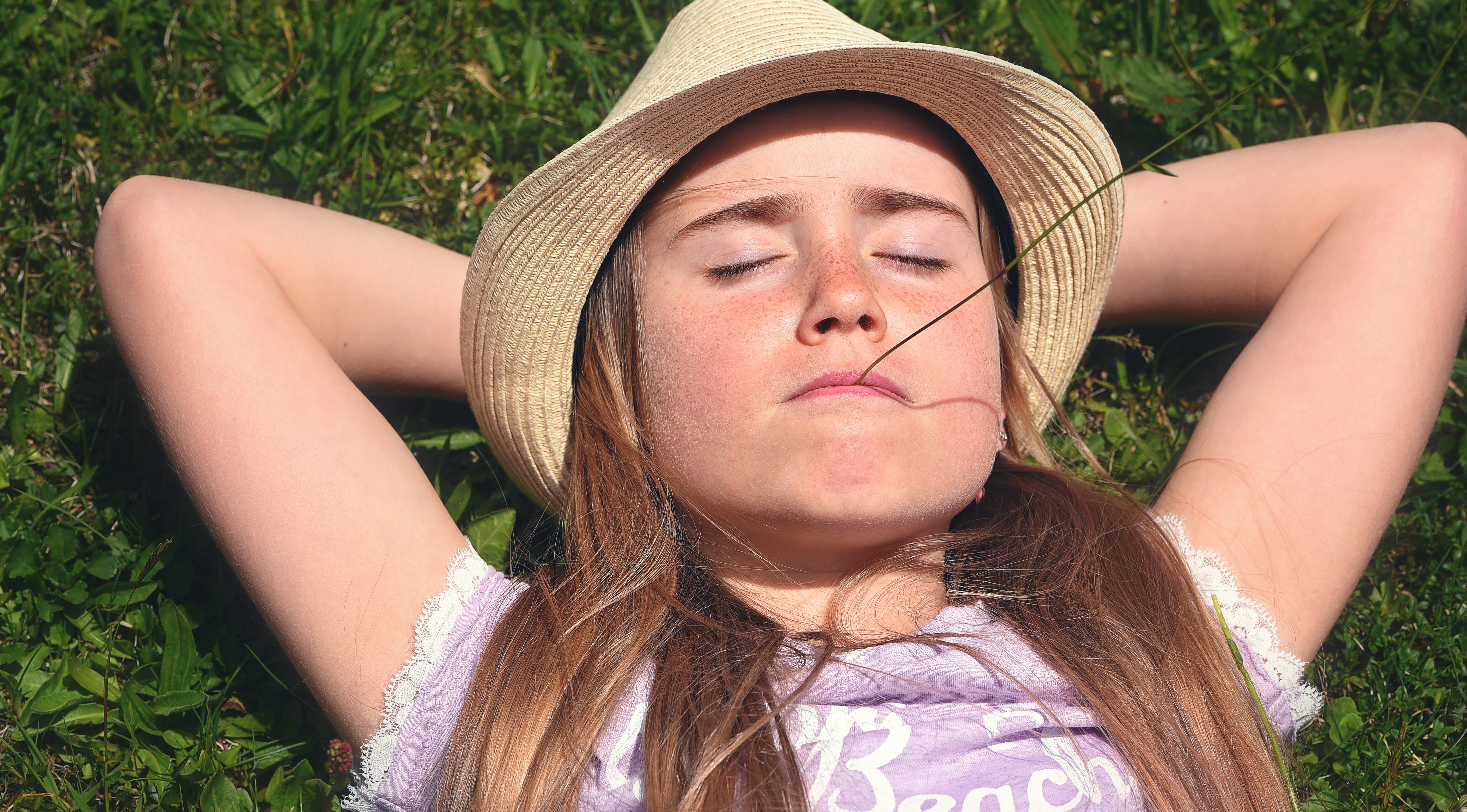 woman in brown sombrero sleeping above green grasses