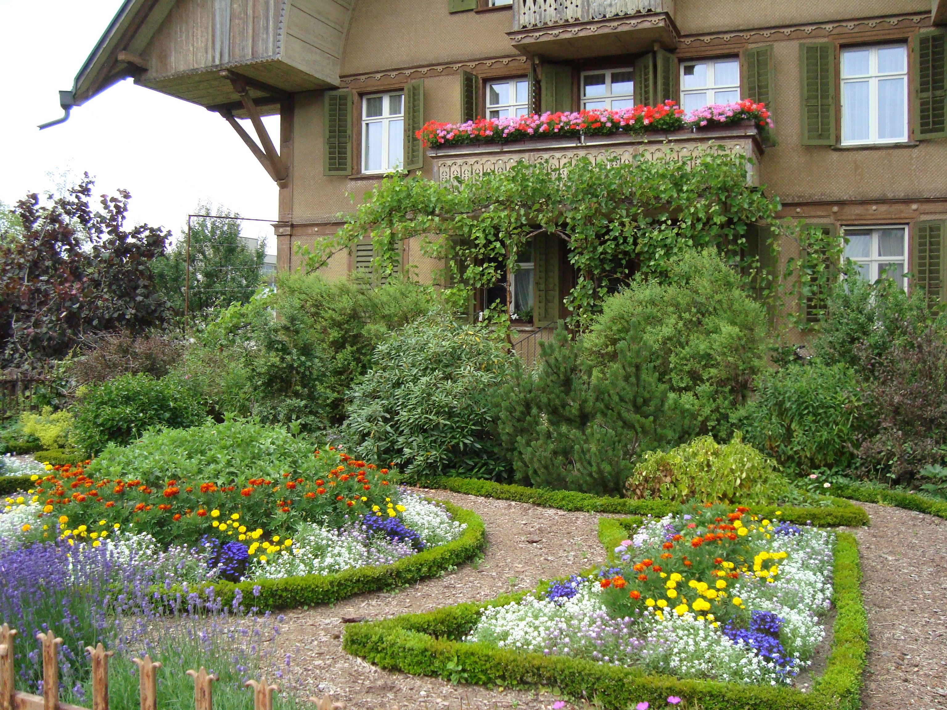 brown concrete two-storey house surrounded of flowers