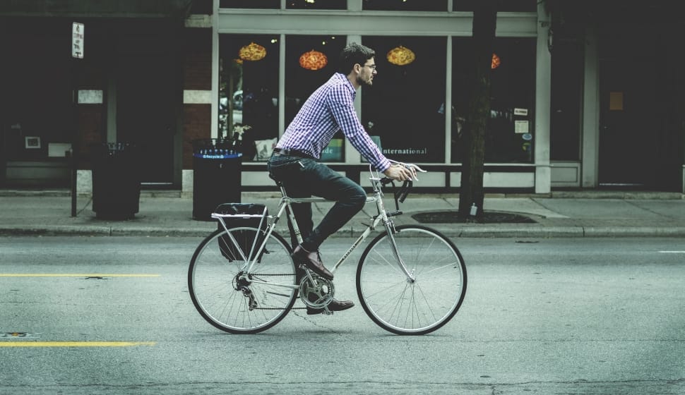 man riding on silver commuter bike preview