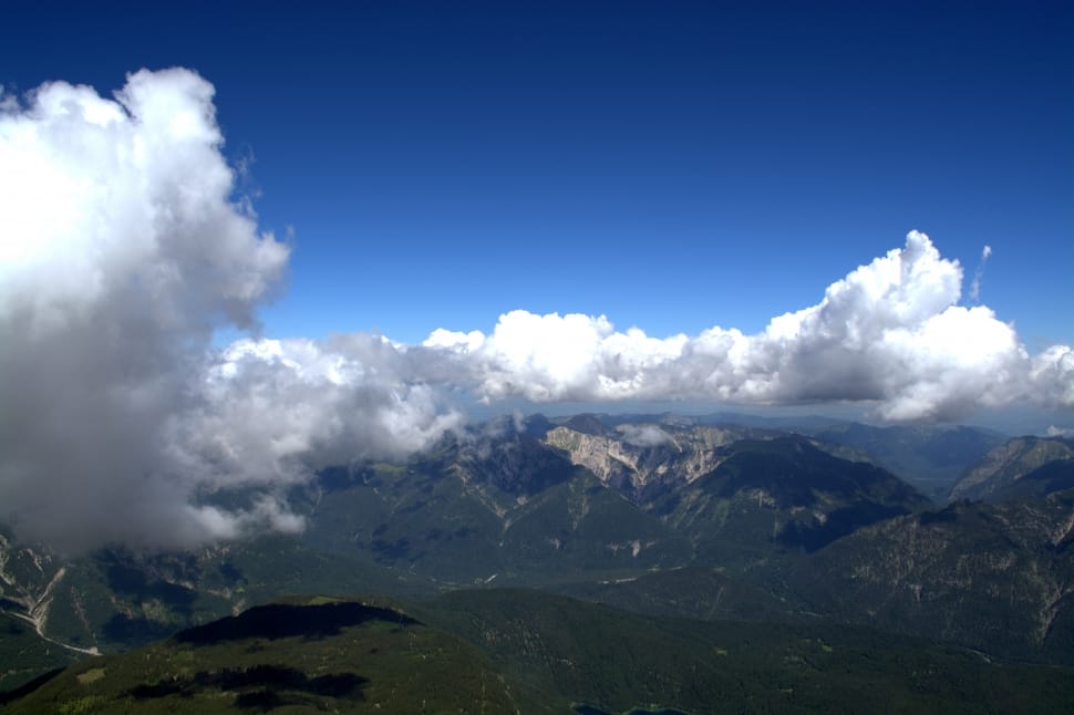 top view of green mountains under white clouds and blue sky during daytime preview