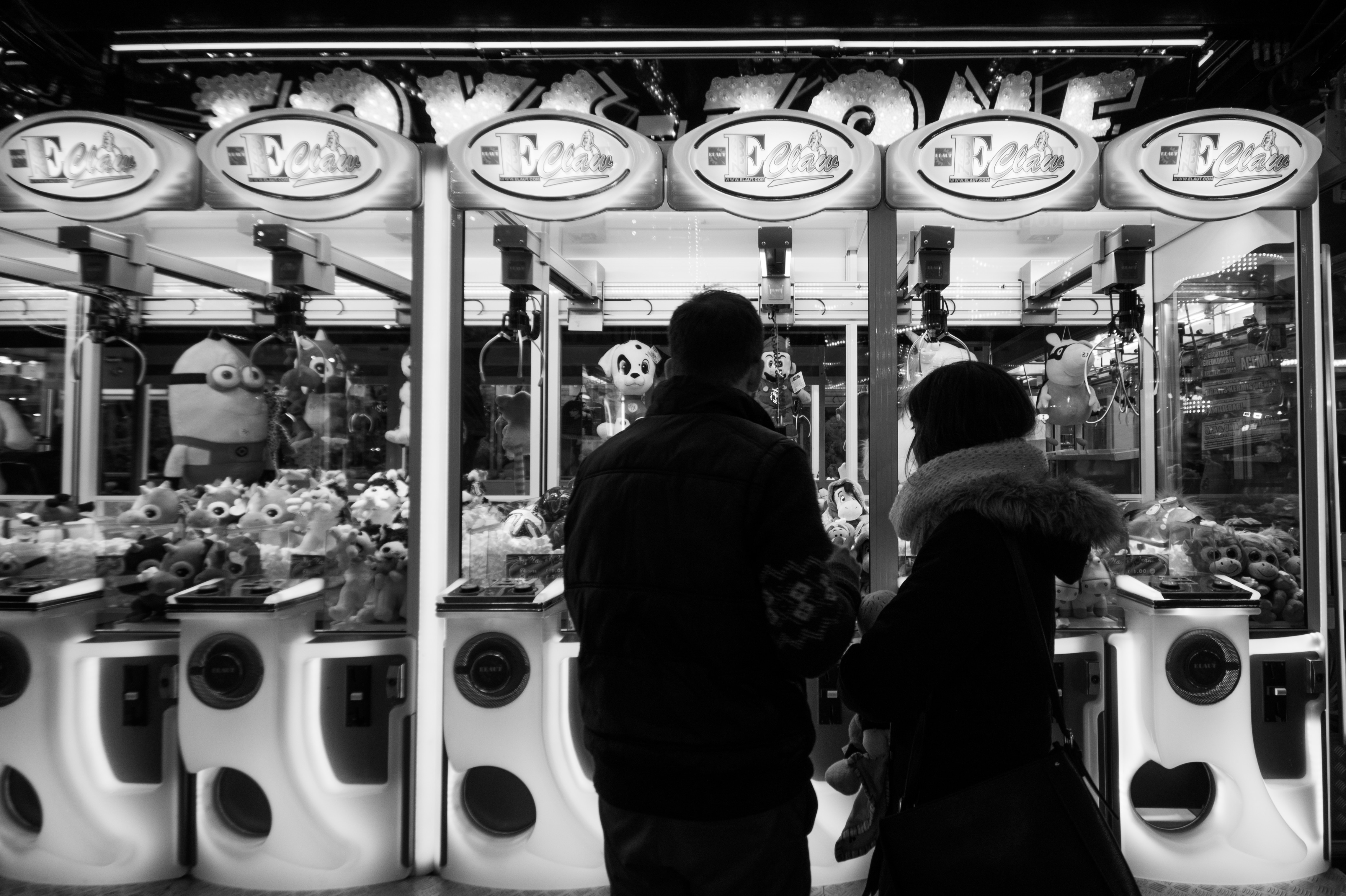 two people in front of claw arcade machine