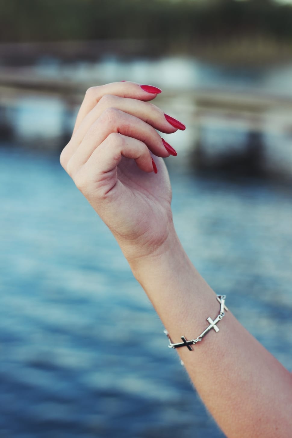 woman wearing silver cross bracelet near sea at daytime preview