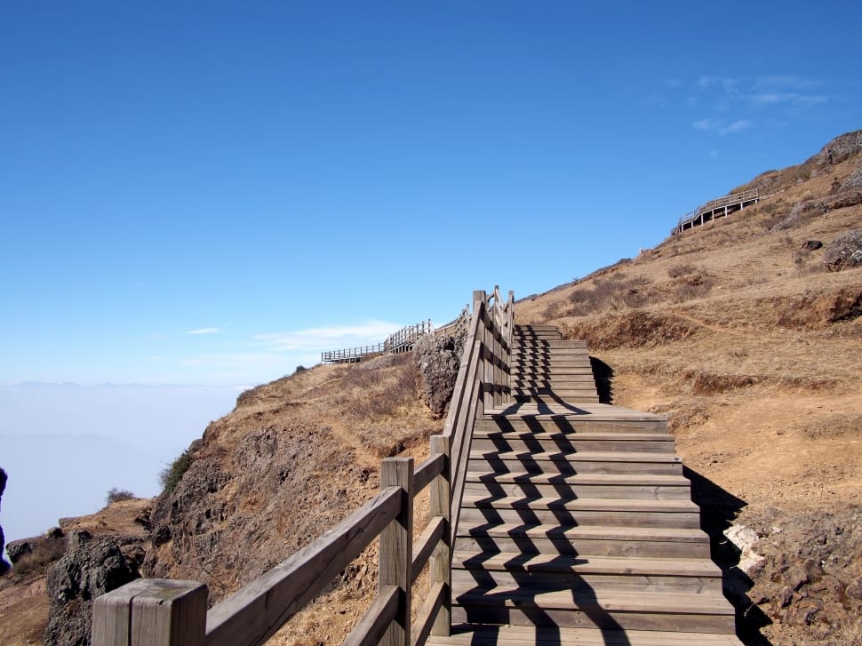brown wooden stairs on mountain under blue sky preview