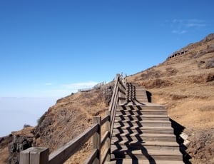 brown wooden stairs on mountain under blue sky thumbnail