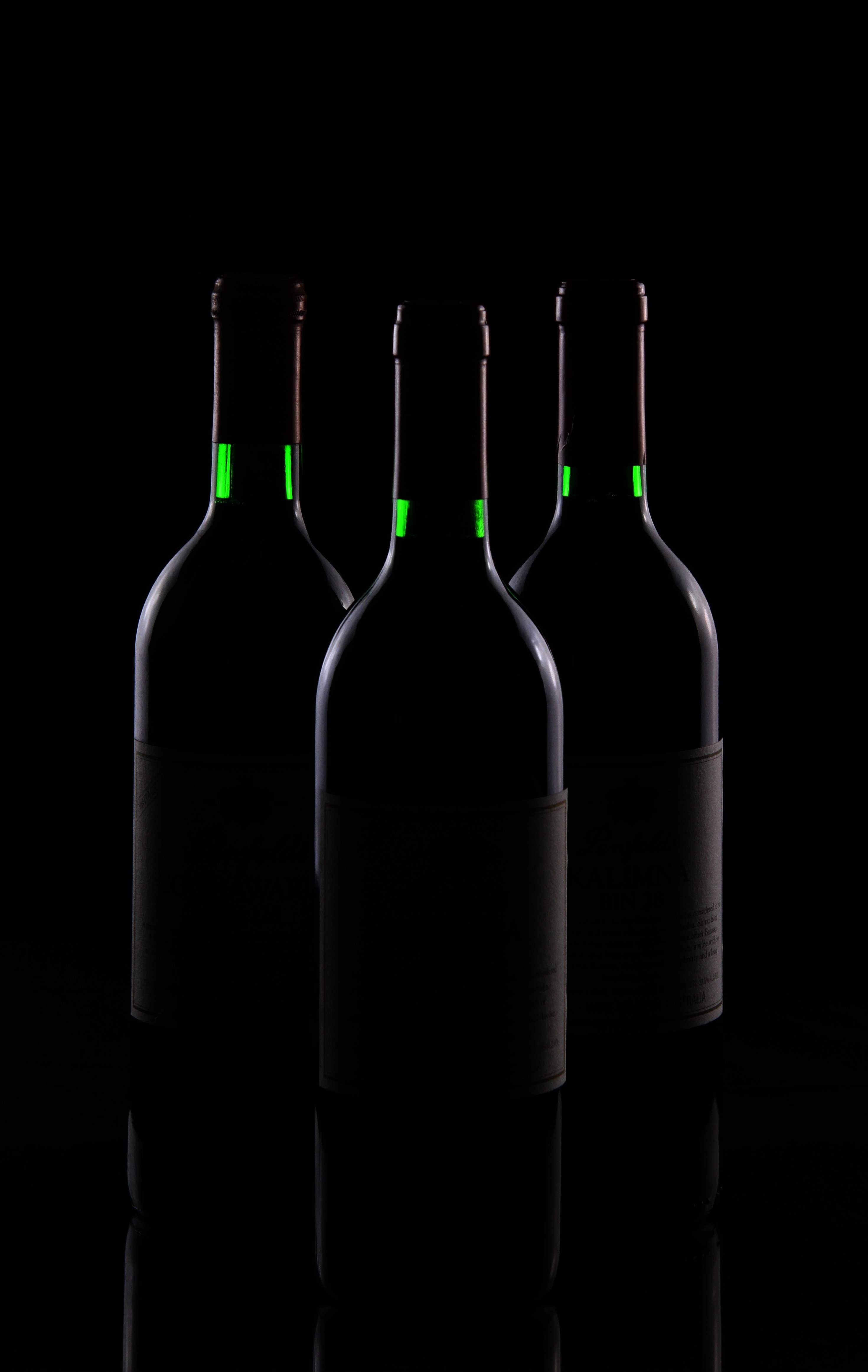 three black bottles on top of black surface
