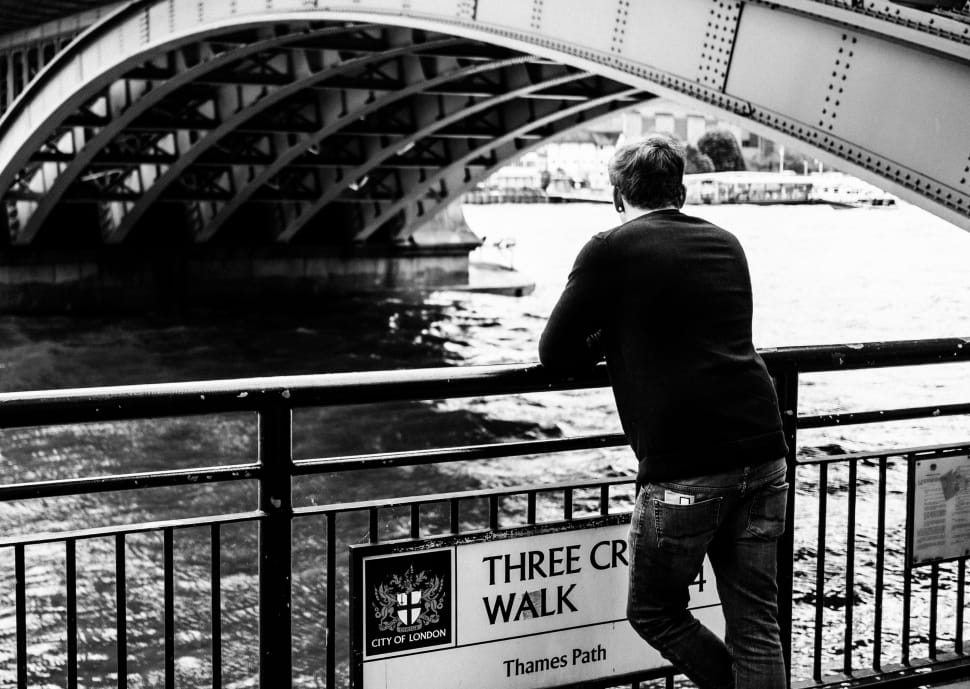 man leaning on river fence grayscale photo preview