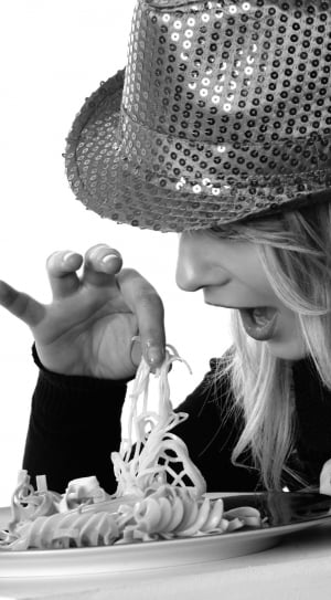 gray scale photo of woman holding pasta wearing hat and long sleeves shirt thumbnail