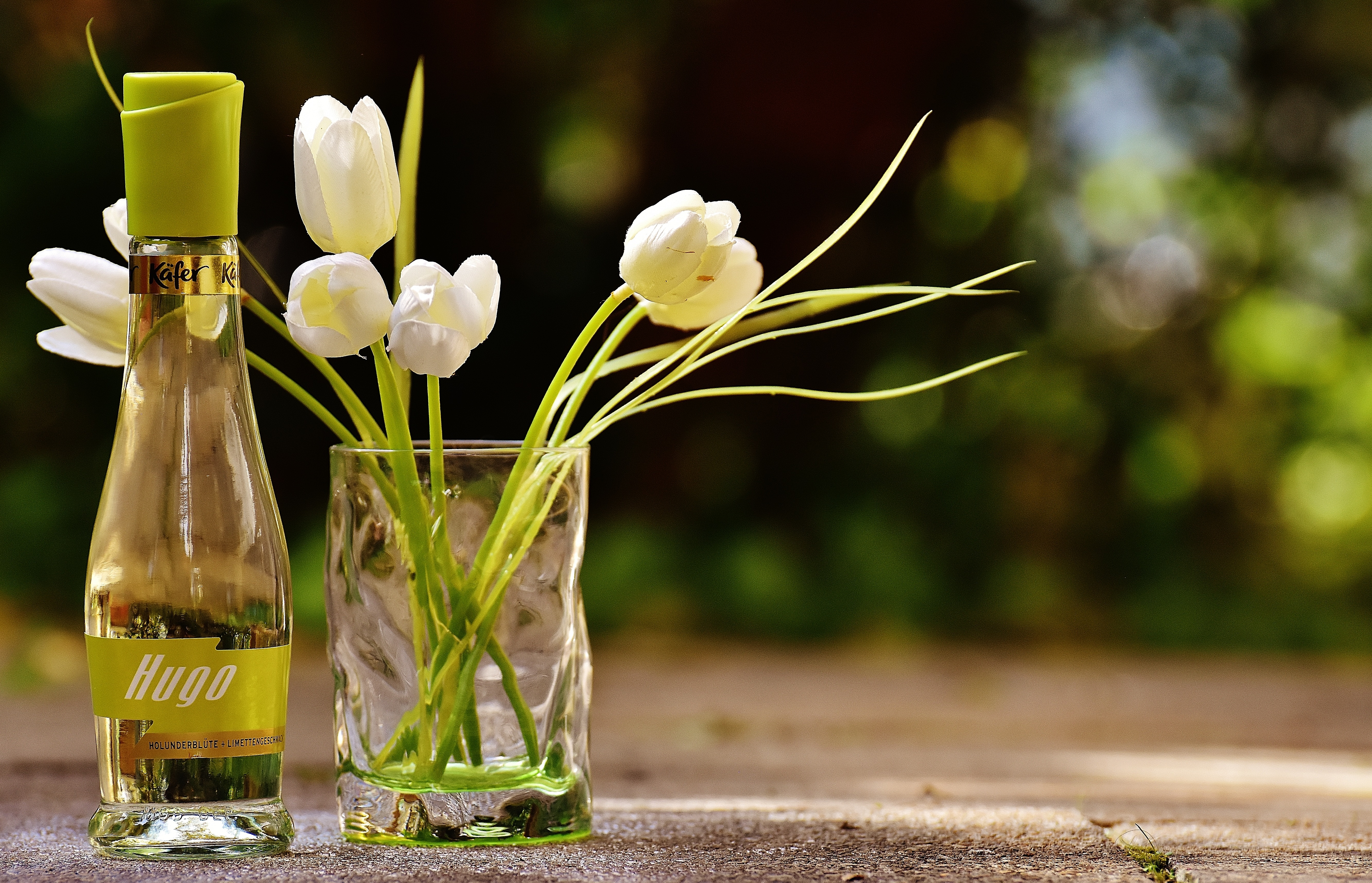 hugo bottle beside white tulips in clear drinking glass