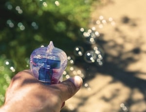 clear bubble gun held by human left hand during daytime thumbnail
