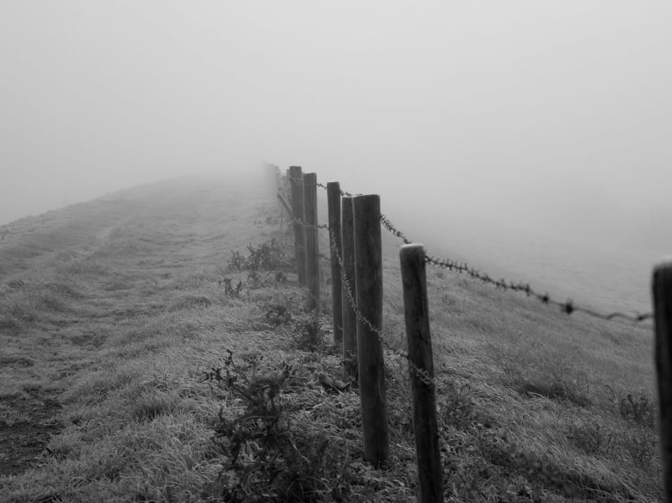 grey scale photo of mountain fence with foggy background during day time preview