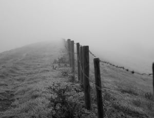 grey scale photo of mountain fence with foggy background during day time thumbnail