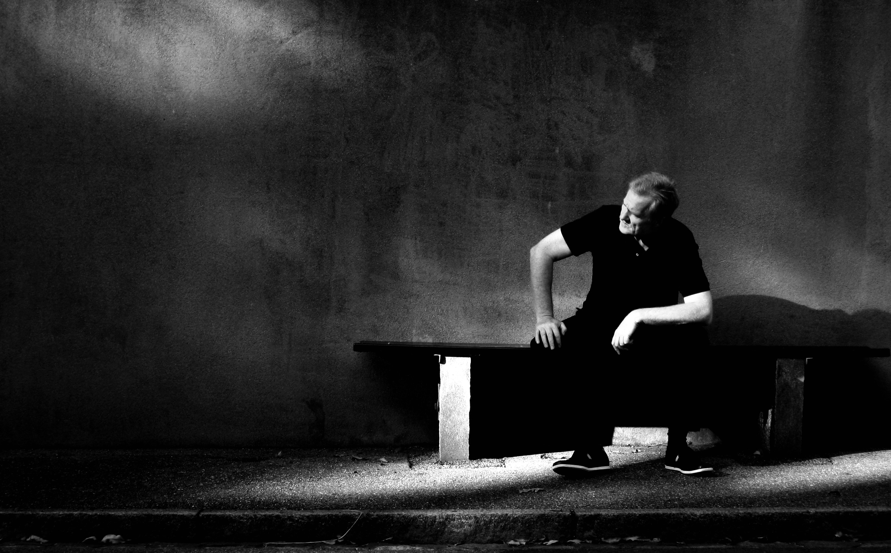 grayscale photo of man sitting on bench