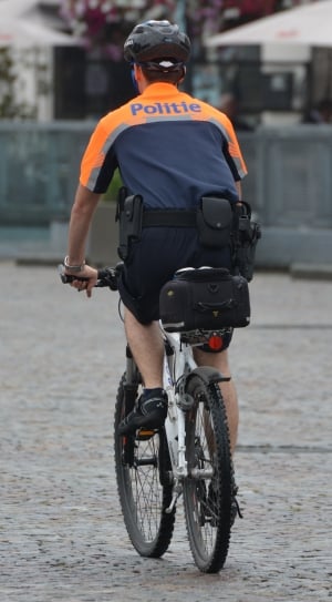 man in grey and orange Politie shirt riding grey mountain bike during daytitme thumbnail
