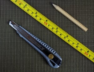 macro shot photography of blue and silver utility knife,yellow tape measure and beige pencil thumbnail